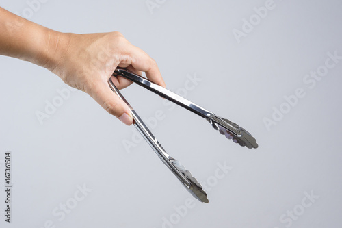 Fotografía Hand holding silver serving kitchen tongs for picking food