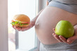 © Artem - Pregnant woman belly holding a plate with junk and healthy food. Concept choice of diet during pregnancy