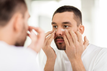 Poster - young man applying cream to face at bathroom