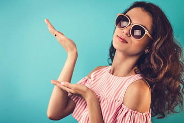 Portrait of a pretty woman in sunglasses pointing on something