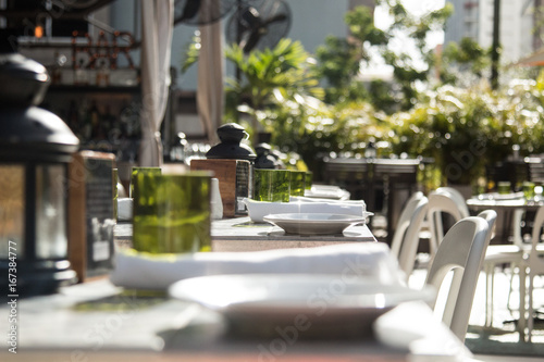 Zdjęcie XXL Letni dzień ustawienie wystrój restauracji z białymi talerzami, zielone okulary i czarne latarnie