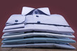 Men's shirts on a wooden table. Folded. Background burgundy.