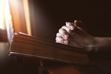 Hands Praying on Holy Bible beside a Window Light, Hope and Religion Concept