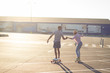 © serejkakovalev - Young couple riding skateboard during sunrise