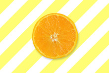 Centered Slice Of Orange On A Yellow Striped Background. Empty Copy Space For Editor's Text.