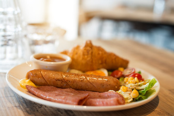 English breakfast with fried eggs, bacon, sausages, beans, toasts and fresh salad