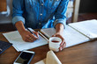 © Trinette Reed/Stocksy - Businesswoman writing on check in her office