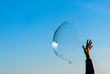 © Carolyn Lagattuta/Stocksy - Hand reaching up to pop a big bubble