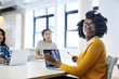 © Cavan Images - Businesswomen working on laptop while sitting in office