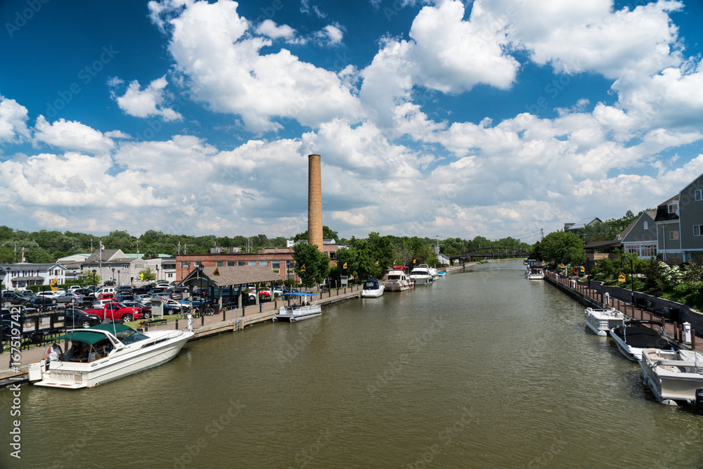 Erie canal with boats and buildings on a summer day in Fairport, New York - obrazy, fototapety, plakaty 