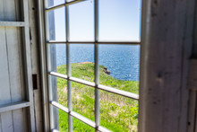Looking Through Old Window Of House With Cliff And Ocean View In Bonaventure Island, Quebec, Canada