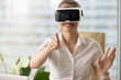 © fizkes - Smiling woman in VR headset enjoying virtual tour, pointing by finger at augmented world, trying to touch 3d ar objects, interacting with digital interface, testing goggles for business, focus on hand