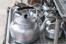 Close Up View. Many Kettles Of Aluminium On Sieve Rack.