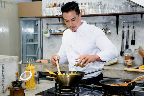 Plakat Azjatycki szef kuchni gotuje jedzenie używać drewnianej kopyści przy kuchnią restauracja