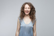 © Yulia - Studio shot of attractive optimistic funny girl with curly hair showing her tongue and blinking eyes while posing against white background. Emotional Caucasian lady making grimace.