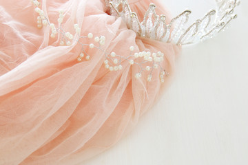 Vintage tulle pink chiffon dress and diamond tiara on wooden white table. Wedding and girl's party concept