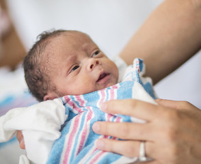 beautiful happy newborn baby boy being held by his mother in the hospital. great healthcare image of