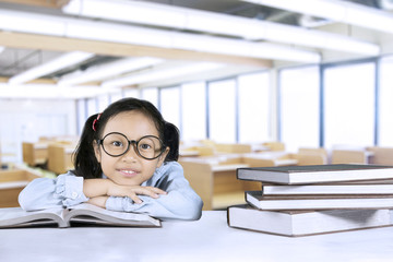 Wall Mural - Cute girl sitting with books in classroom