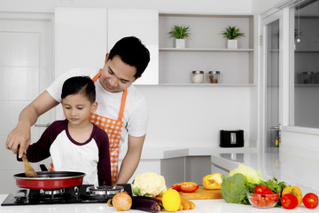 Young father teaches his son to cook