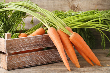 Fresh and ripe carrots in crate on wooden table