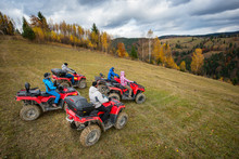 Five ATV Riders On Off-road Quad Bikes On The Hillside At The Background Of Autumn Forest With Colorful Trees And Mountains. Top View