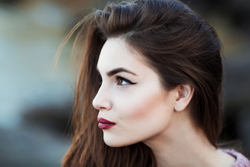 Beautiful young woman. Dramatic outdoor portrait of sensual brunette female with long hair. Sad and serious girl.