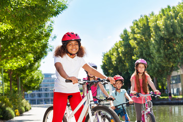 Wall Mural - African girl cycling with friends at city park