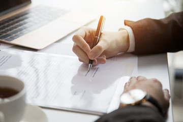 Businessman signing documents on the table.