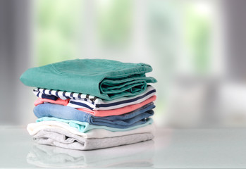 Wall Mural - Stack colorful cotton clothes on table empty space background.
