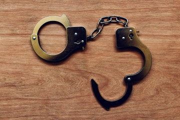 Handcuffs on wooden background