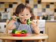 baby girl eating  vegetable at home