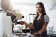 © Liubov Levytska - Female cafe owner preparing coffee using a portafilter and a coffee machine