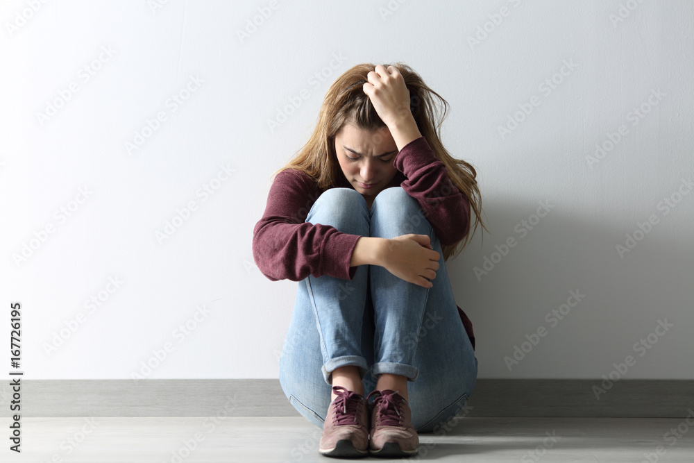 Front view of a sad woman sitting on the floor - obrazy, fototapety, plakaty 