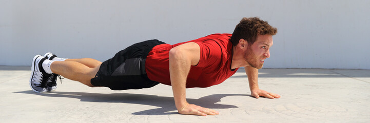 Wall Mural - Pushup fitness man banner doing push-ups workout bodyweight exercise on gym floor. Athlete working out chest muscles strength training outdoors panoramic crop.