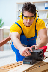 Repairman carpenter polishing a wooden board with an electric po