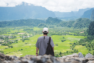 Wall Mural - young man with backpack enjoying beautiful landscaped nature view on top of the mountain in laos, tr