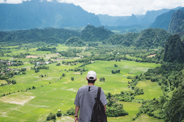 Wall Mural - young man with backpack enjoying beautiful landscaped nature view on top of the mountain in laos, tr