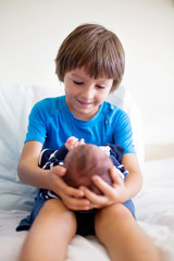 Wall Mural - Cute boy, brother, meeting for the first time his new baby brother at hospital