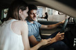 © Drobot Dean - Young smiling couple sitting at the front seats of their new car
