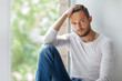 © GVS - Handsome thoughtful man touching his hair relaxing on window sill