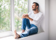 © GVS - Handsome smiling man relaxing on window sill
