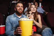 © Drobot Dean - Young laughing couple holding a big popcorn bucket