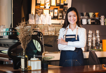 Poster - Asian female barista wear jean apron crossed her arms at counter bar with smile face,cafe service concept,owner business start up