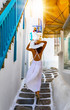 Elegante Frau in weißem Kleid läuft durch die weißen Gassen von Mykonos Stadt, Griechenland