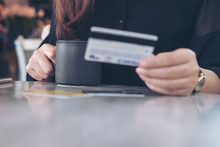 Closeup Image Of A Woman's Hand Holding Credit Cards And Black Coffee Cup On The Table