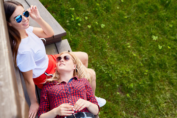 Wall Mural - Pretty serene girls having rest on wooden bench in natural environment