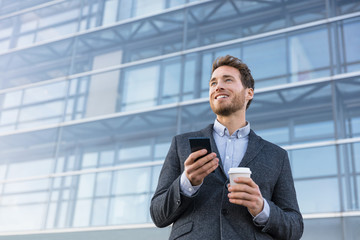 Wall Mural - Business man holding phone drinking coffee at bank office thinking of the future. Aspirational businessman dreaming of career hope.