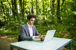 © F8  \ Suport Ukraine - Businessman sitting at the office desk work at laptop computer in green forest park. Freelancer working on office table in green park. Business portrait.