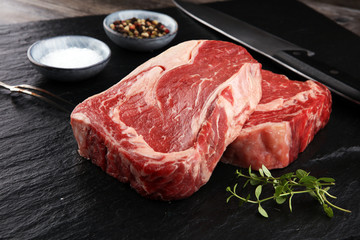 Wall Mural - Raw fresh meat Ribeye Steak, seasoning and meat fork on dark background