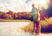 Grandfather And Grandson Fishing On River Berth